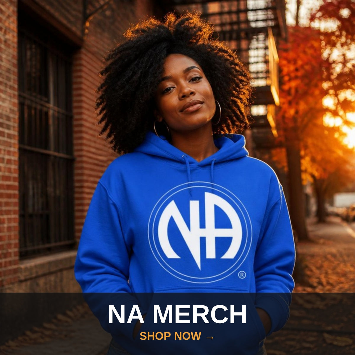 NA merchandise collection - woman in royal blue NA logo hoodie at fall sunset